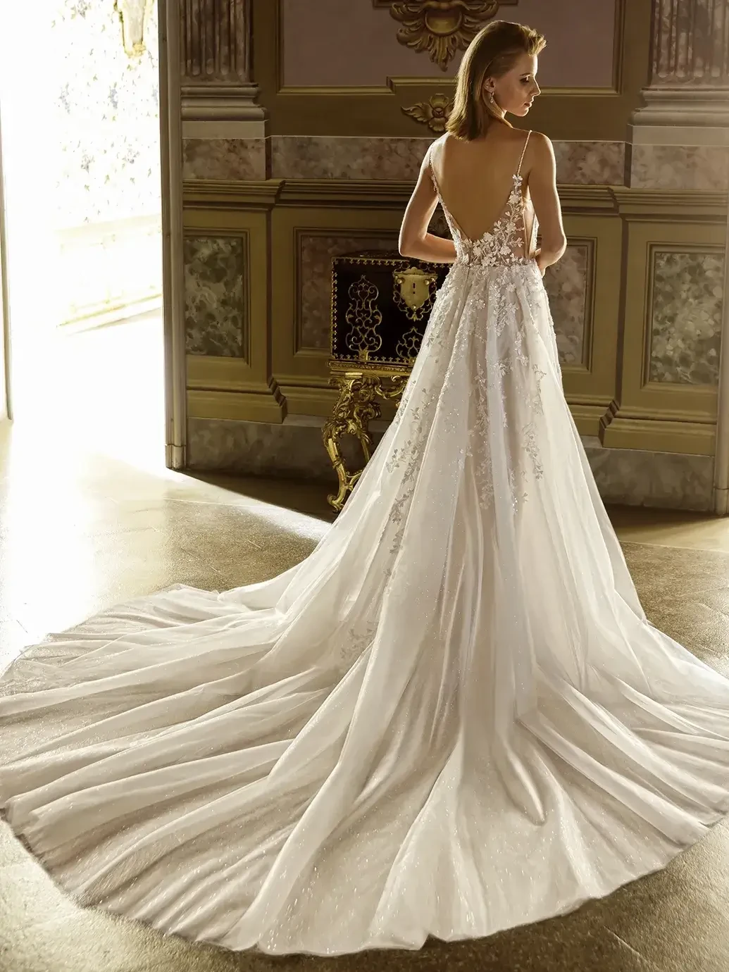Model is wearing a sleeveless a-line tulle bridal gown with a lace bodice and plunging neckline 