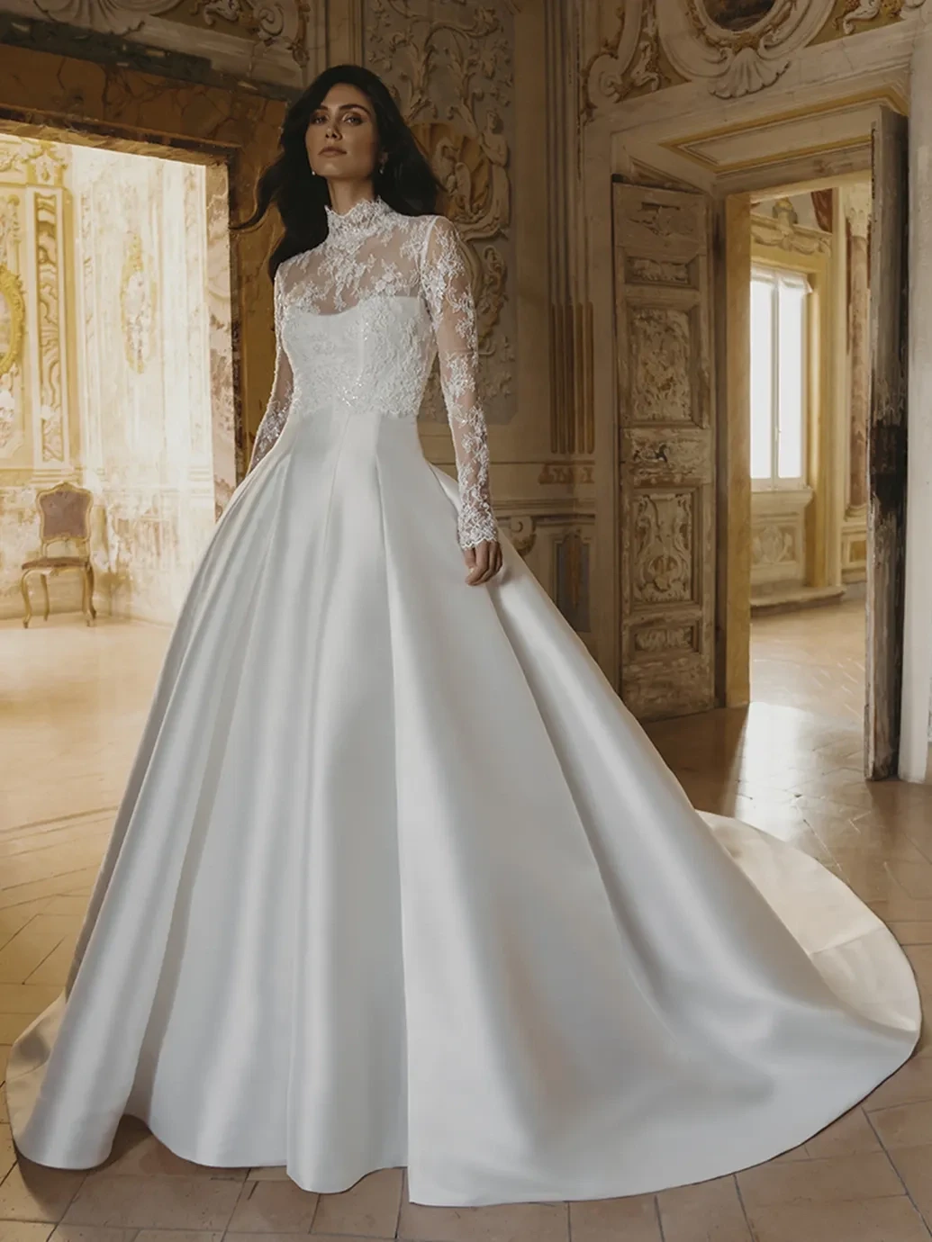 A model wears a high-neck lace wedding gown with a full satin skirt in an ornate room.