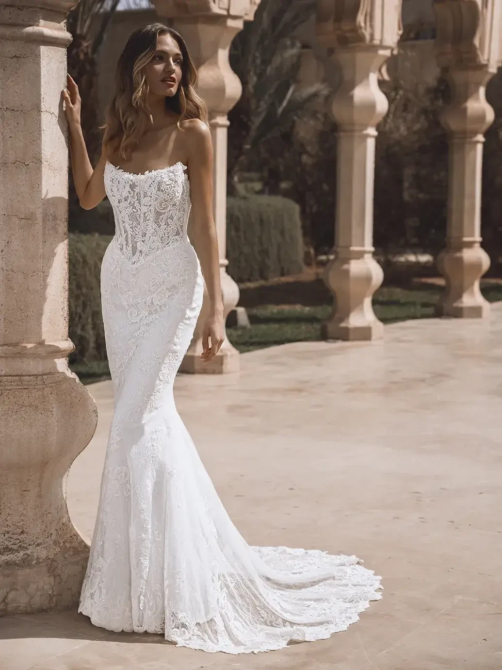 model is wearing a lace strapless fitted wedding dress with detachable sleeves