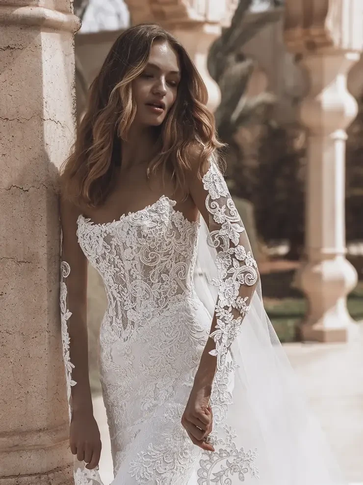 model is wearing a lace strapless fitted wedding dress with detachable sleeves